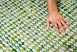 Cashew Loop — Green wool rug shown flat and in full on a plain white ground, seen from a three-quarter angle (third pass)