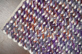 Textured pile close-up of purple wool rug