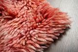 Pink shaggy rug styled near a bed