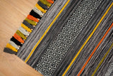 Pom-pom tassel detail on grey chenille rug