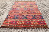 Red Afghan style kilim rug in a living room setting
