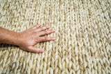Beige braided wool rug laid in a cozy reading nook