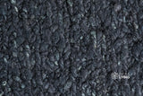 Black wool rug under a bed lifestyle shot