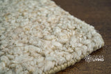 Corner detail of handwoven beige wool rug
