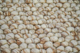 Beige pebble wool rug placed under a coffee table