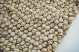 Corner detail of beige chunky pebble wool rug edge