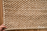 Beige wool rug styled in a bedroom