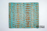 Handwoven turquoise geometric rug shown in a bedroom setting