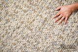 Taupe grey wool rug edge close-up highlighting knit pattern