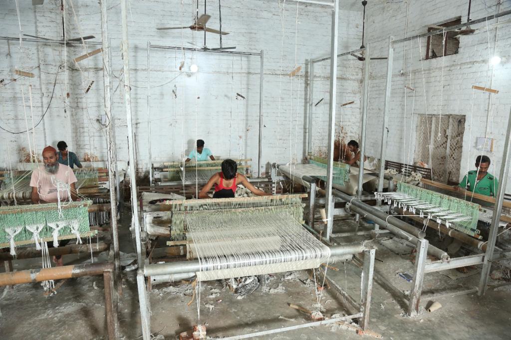 Indian master weavers at work on a hand-knotted wool rug at a Bhadohi loom