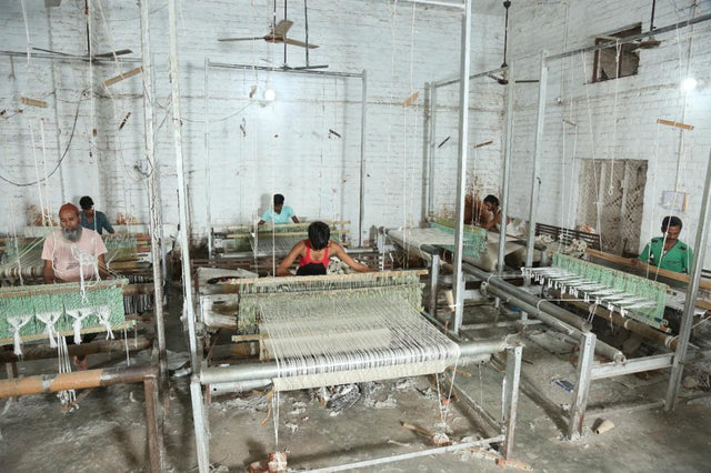 Indian master weavers at work on a hand-knotted wool rug at a Bhadohi loom