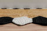 Natural jute braided runner rug with black and white border, flat lay