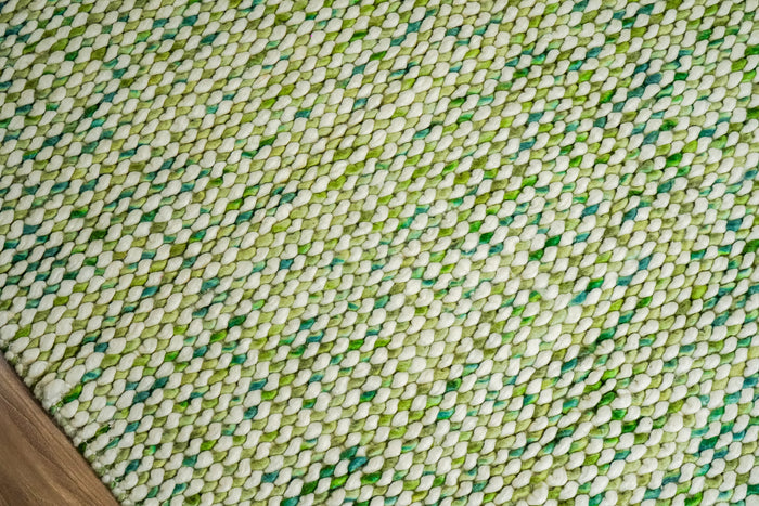 Green Cashew Loops — close-up of the chunky loop weave, raised pile, and edge finish beside wood flooring