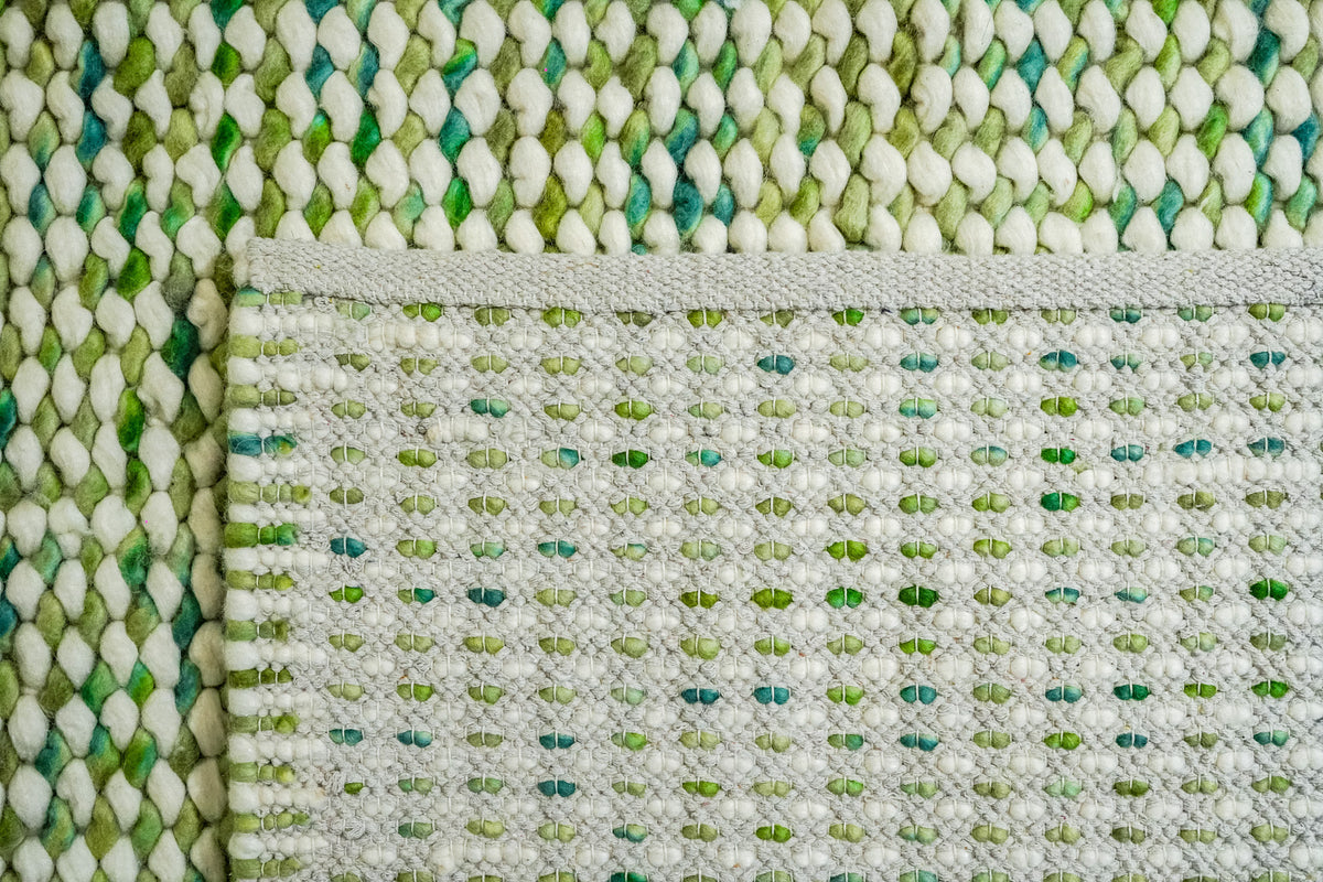 Green Cashew Loop — folded corner revealing the woven underside and bound edge of the chunky wool loop rug