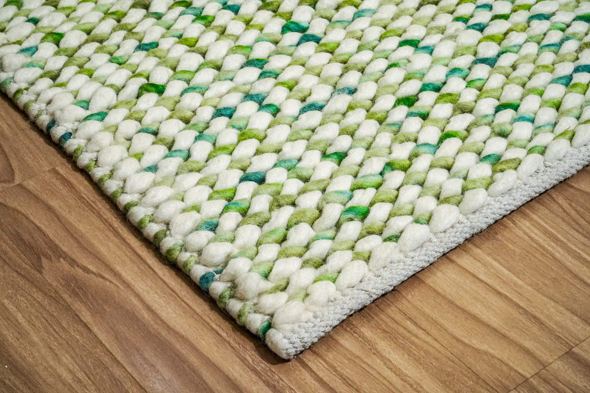 Green Cashew Loop — angled corner view of the chunky wool loop rug with a pale finished edge