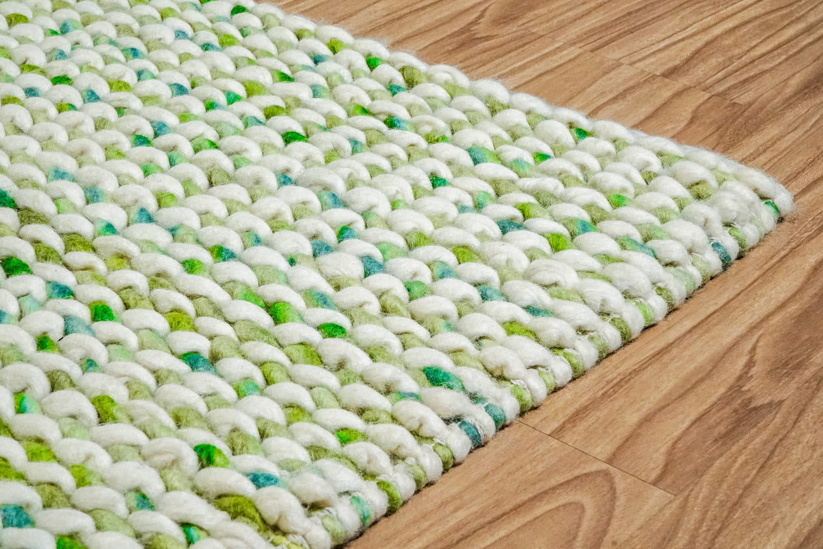Cashew Loop — angled corner close-up showing green accents between raised ivory wool loops