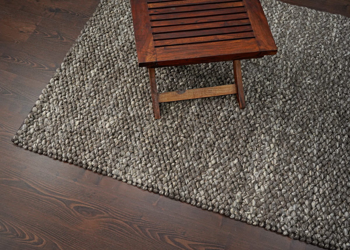 Brown Cashew Loops — wool rug styled in a living room beneath a wooden table on dark flooring