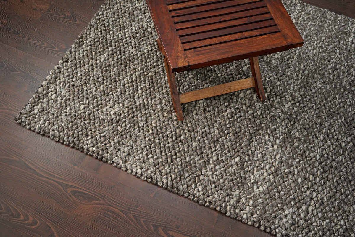 Brown Cashew Loops — wool rug viewed from above at an angle beneath a slatted wooden table