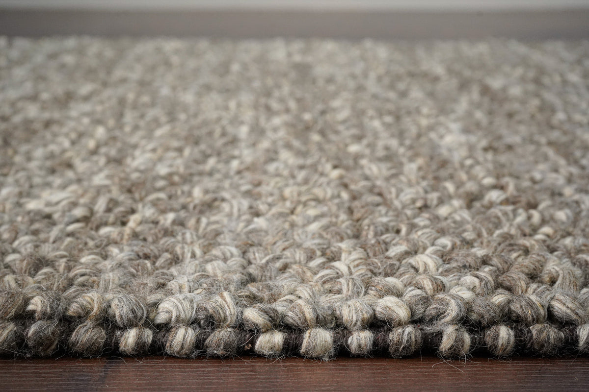Brown Cashew Loops — wool rug seen at floor level, showing the raised loop surface along the edge