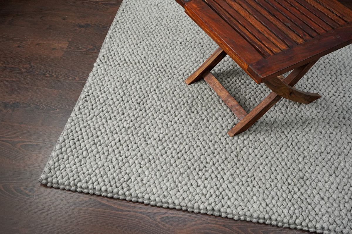 Gray Cashew Loops — wool rug styled in a living room beneath a wooden chair on a dark wood floor
