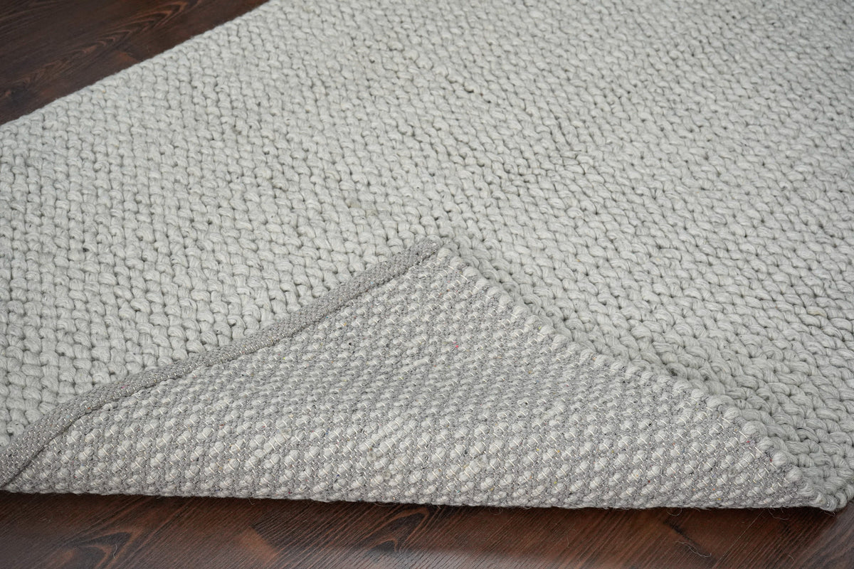 Gray Cashew Loops — wool rug with a broad folded corner revealing the back against the looped face