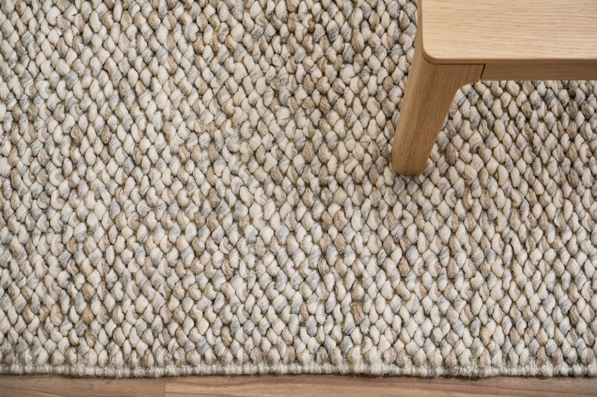 Gray Cashew Loops — wool rug with rounded loops and a finished edge beneath a wood table leg