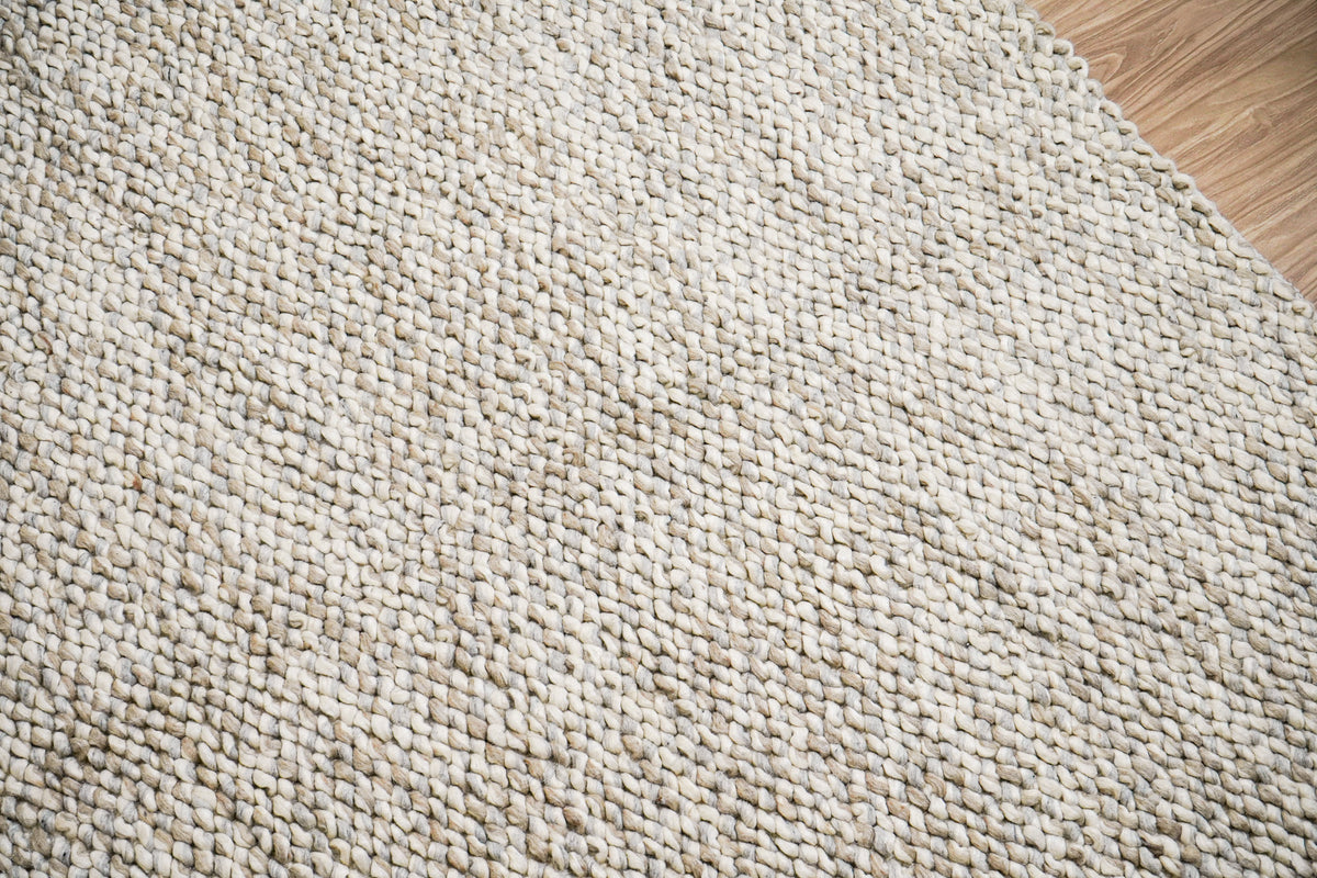 Gray Cashew Loops — wool rug in an angled surface view with wood flooring visible at the upper right