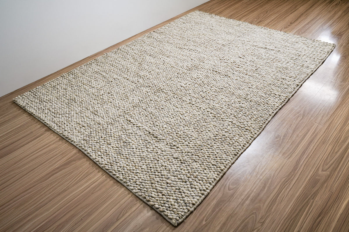 Gray Cashew Loops — wool rug shown in full at an angle beside a plain wall