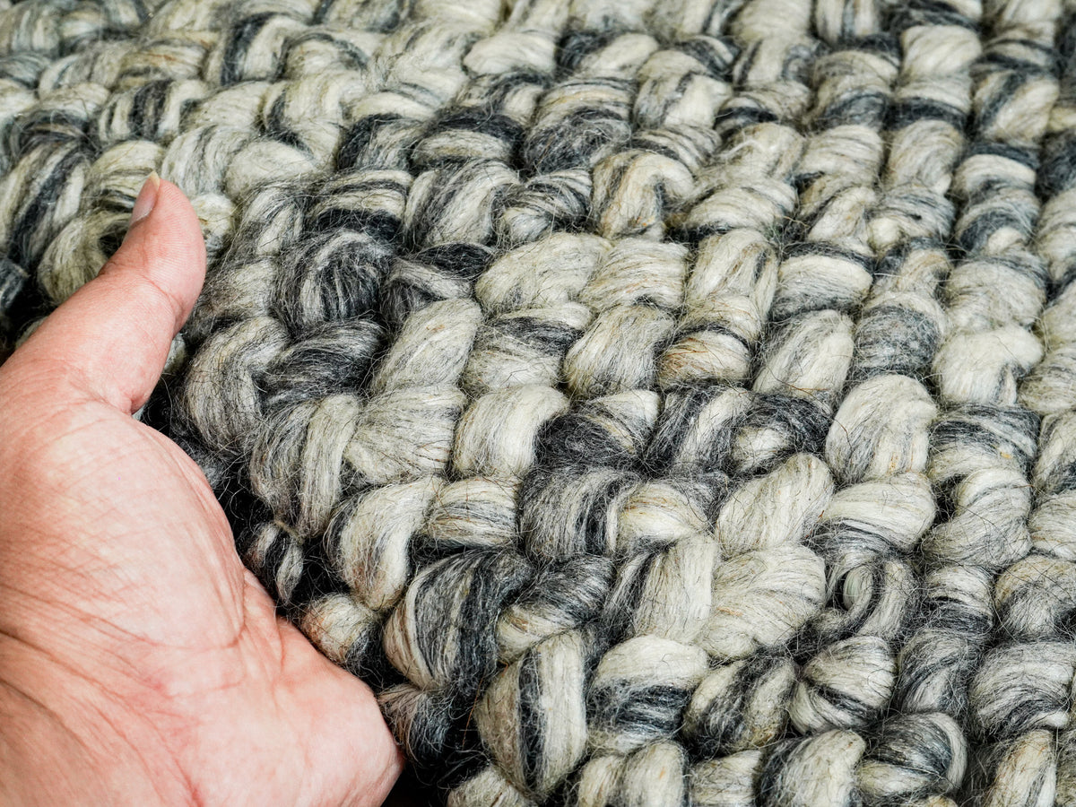 Gray Cashew Loops — close-up of the weave, chunky loop pile and edge finish beside a hand