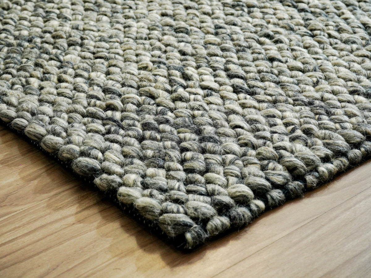 Gray Cashew Loops — Wool rug showing a rounded corner and thick loop texture on a wood floor
