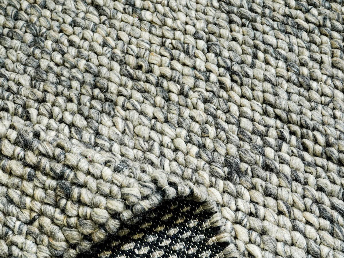 Gray Cashew Loops — Wool rug with a folded corner revealing a small section of the underside