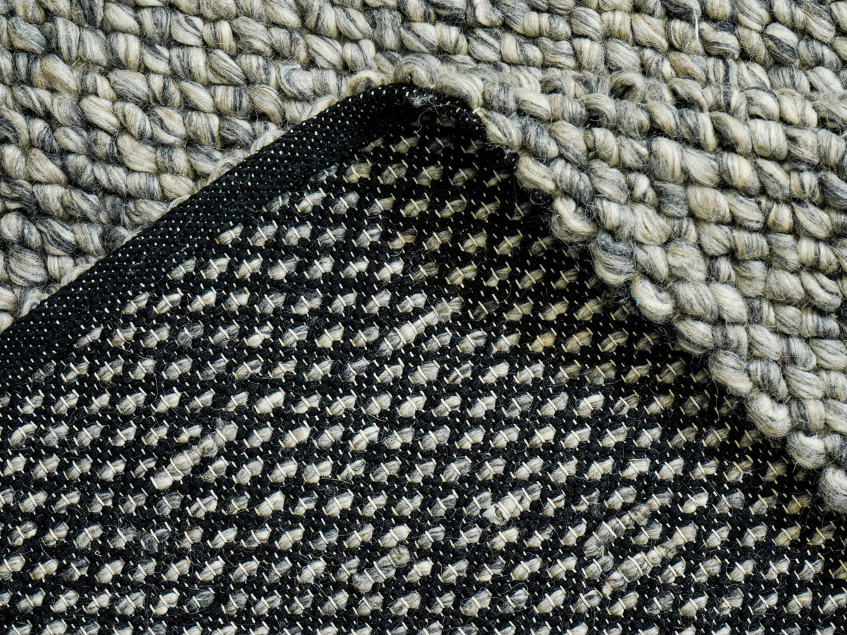 Gray Cashew Loops — Wool rug with a lifted edge exposing the underside and narrow edge finish