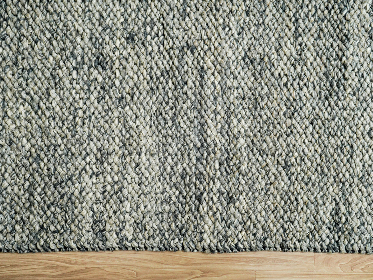 Gray Cashew Loops — Wool rug with its straight lower edge visible against a strip of wood flooring