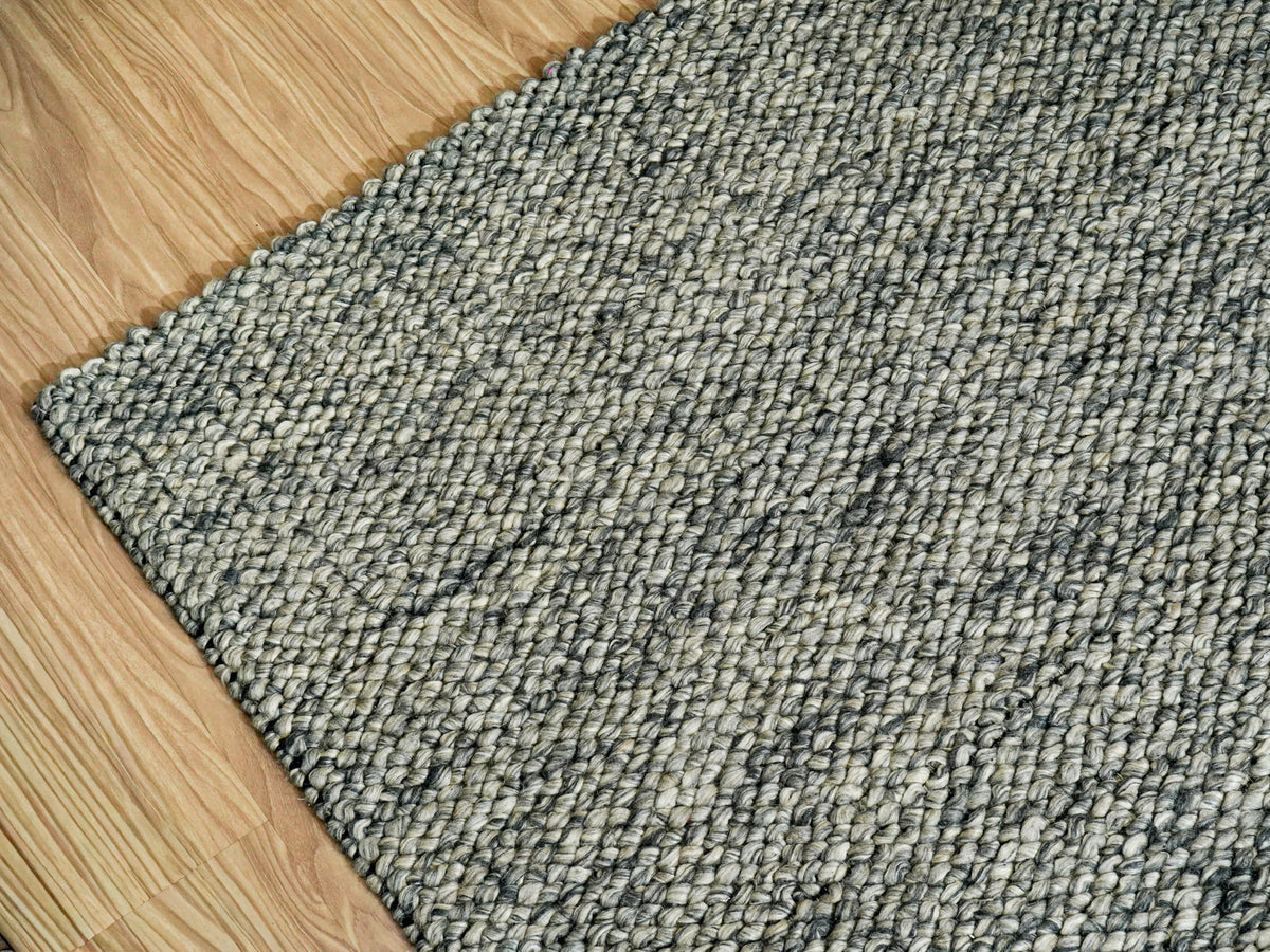 Gray Cashew Loops — Wool rug showing the left corner and adjacent edges from an angled overhead view