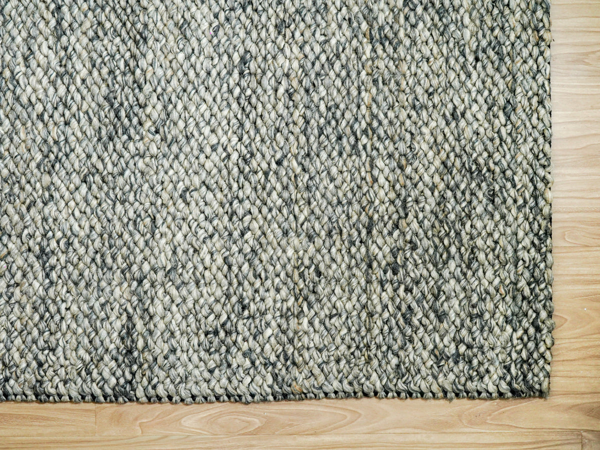 Gray Cashew Loops — Wool rug with the lower right corner framed by wood flooring