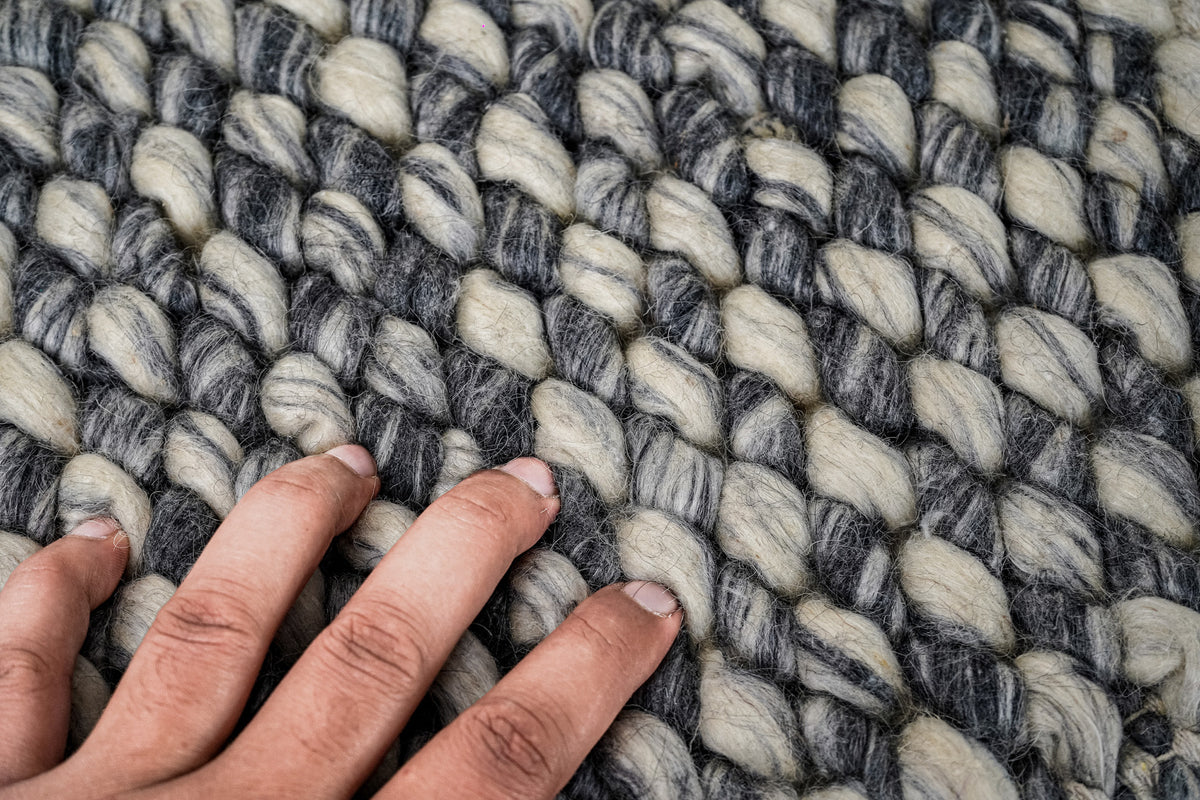 Gray Cashew Loops — Wool rug texture shown beside fingertips for a close view of loop scale