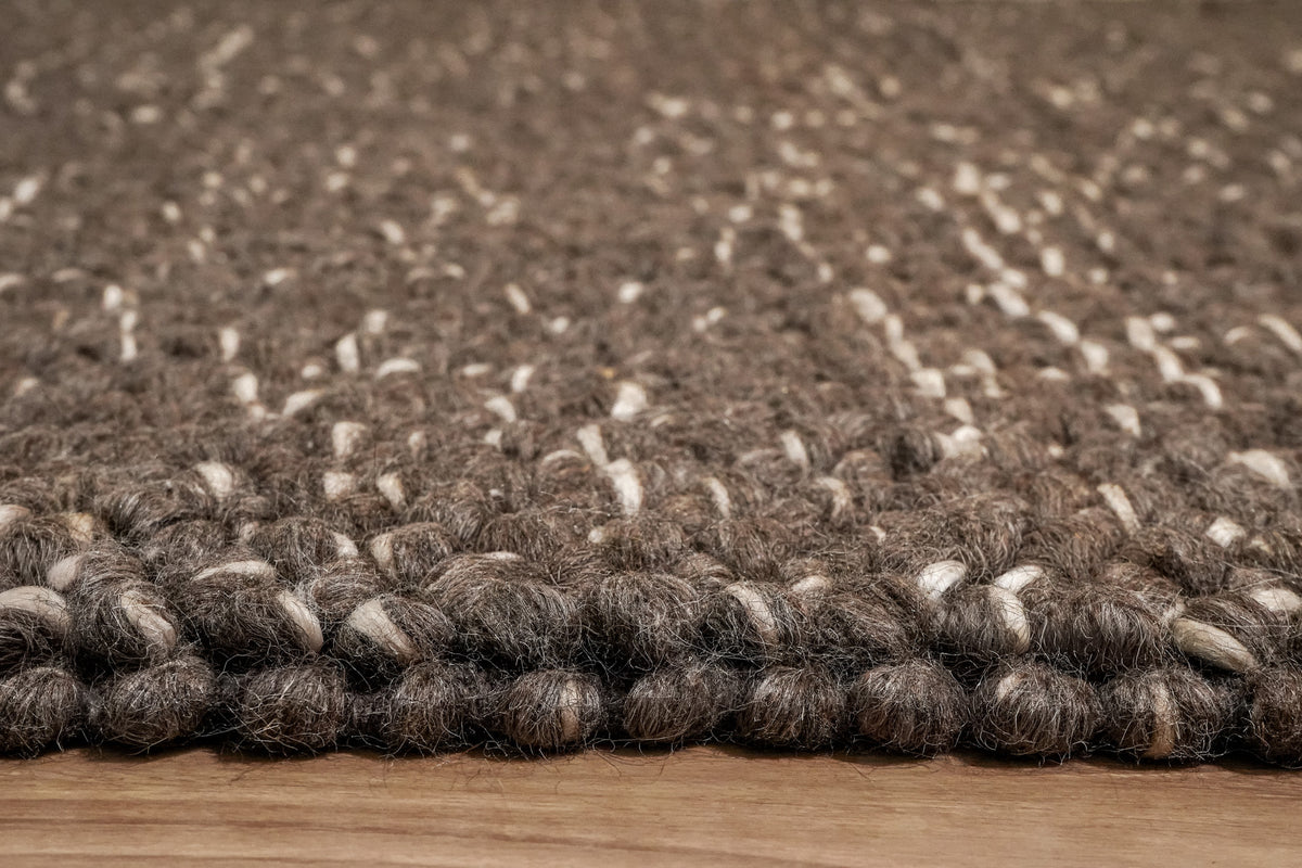 Cashew Loops — brown wool rug viewed at floor level, showing raised loops and the finished edge