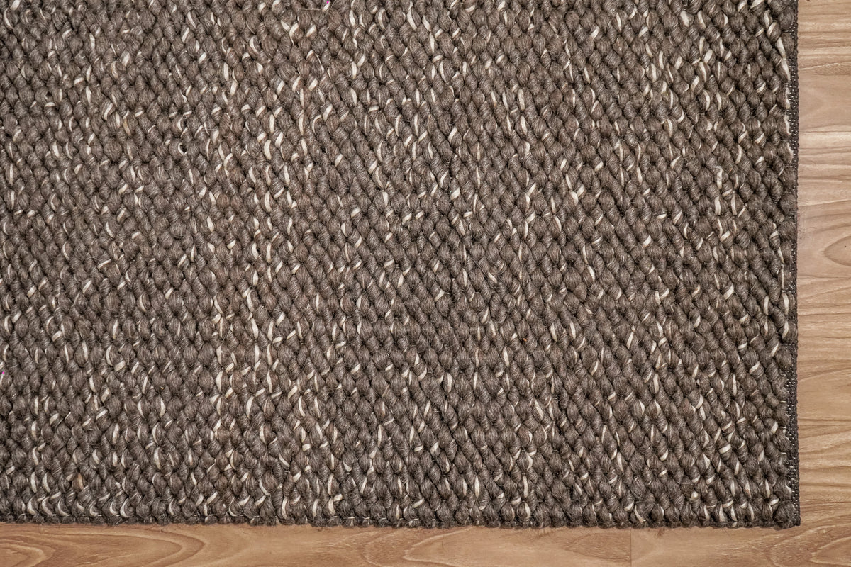 Cashew Loops — overhead detail of the brown wool rug's lower corner and narrow dark border