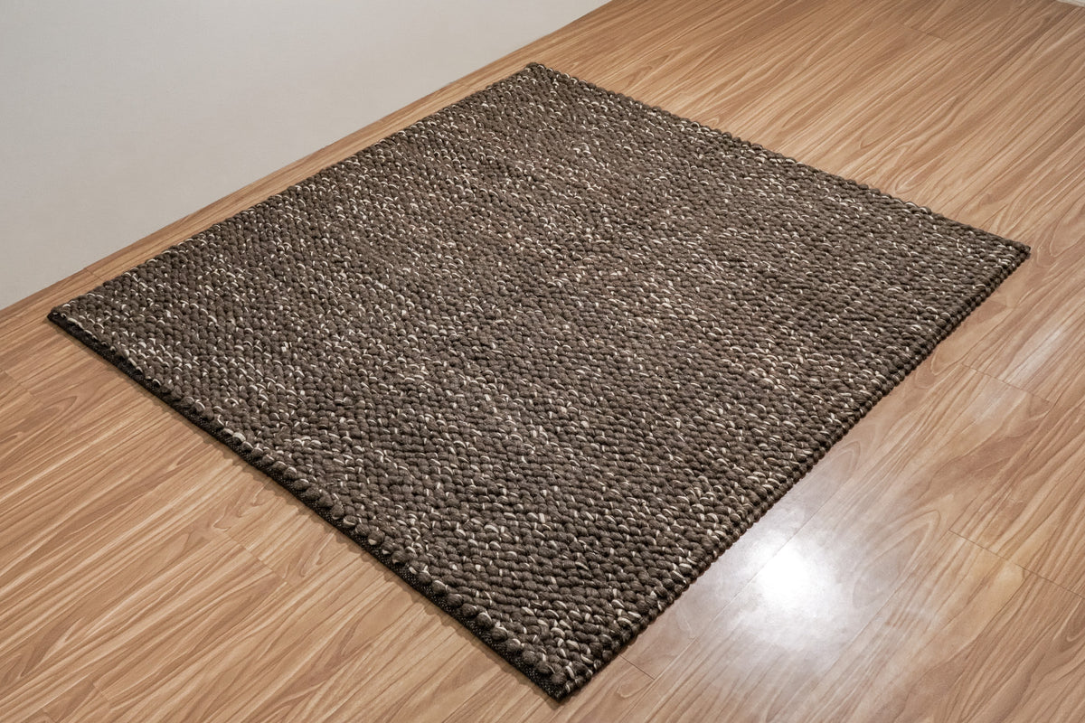 Cashew Loops — full brown wool rug viewed diagonally on a wood floor