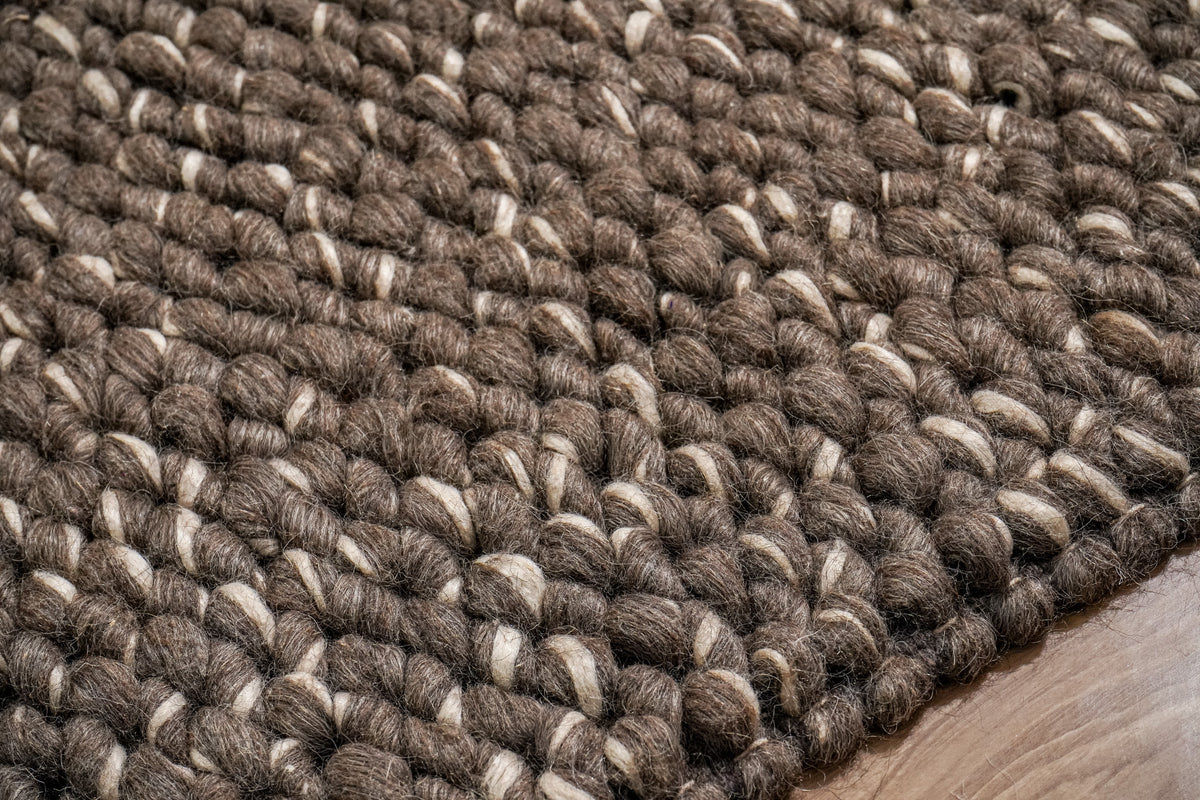 Cashew Loops — close-up of brown wool loops with ivory wraps beside the rug's edge
