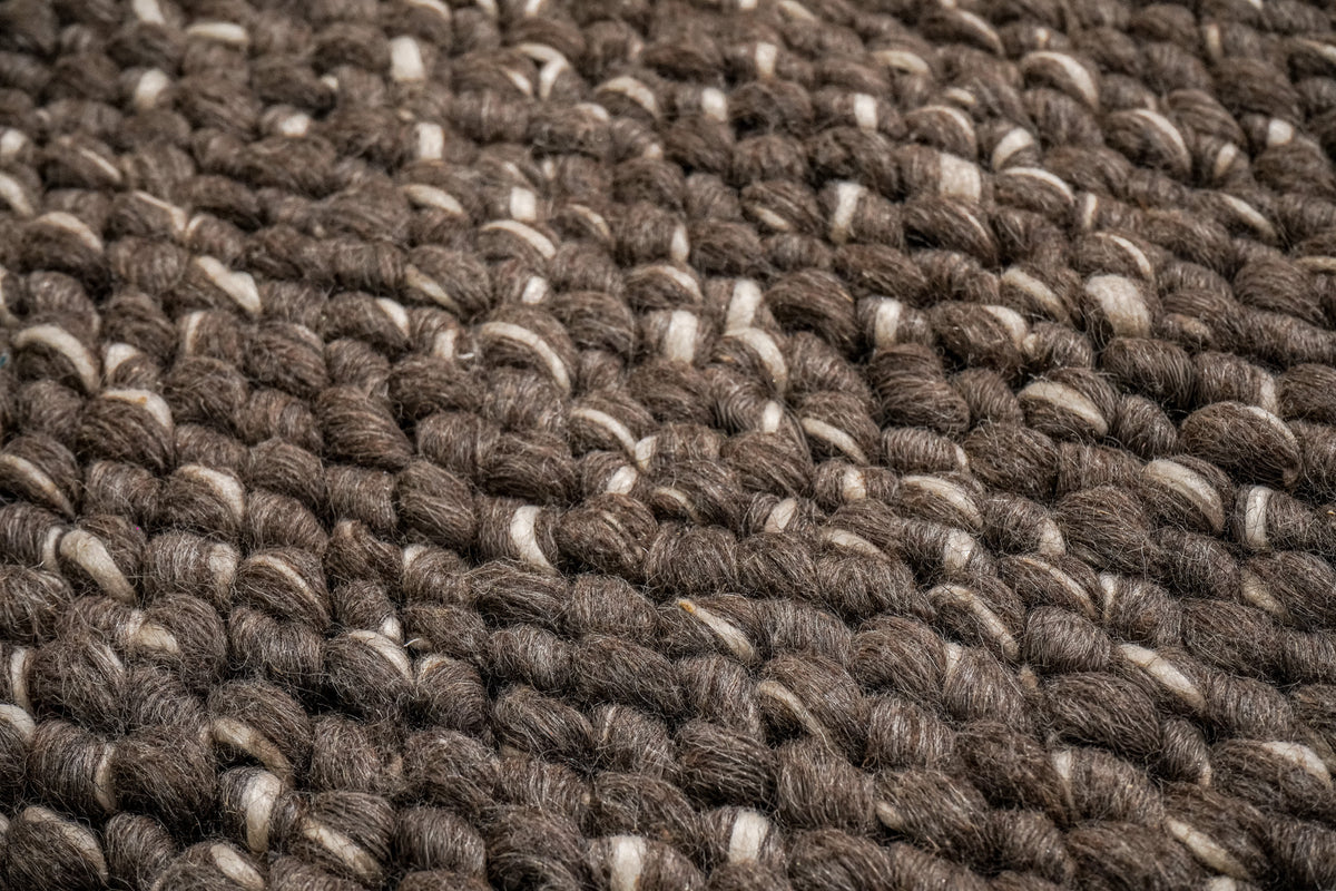 Cashew Loops — macro view across the brown wool rug's rounded loops and ivory accents