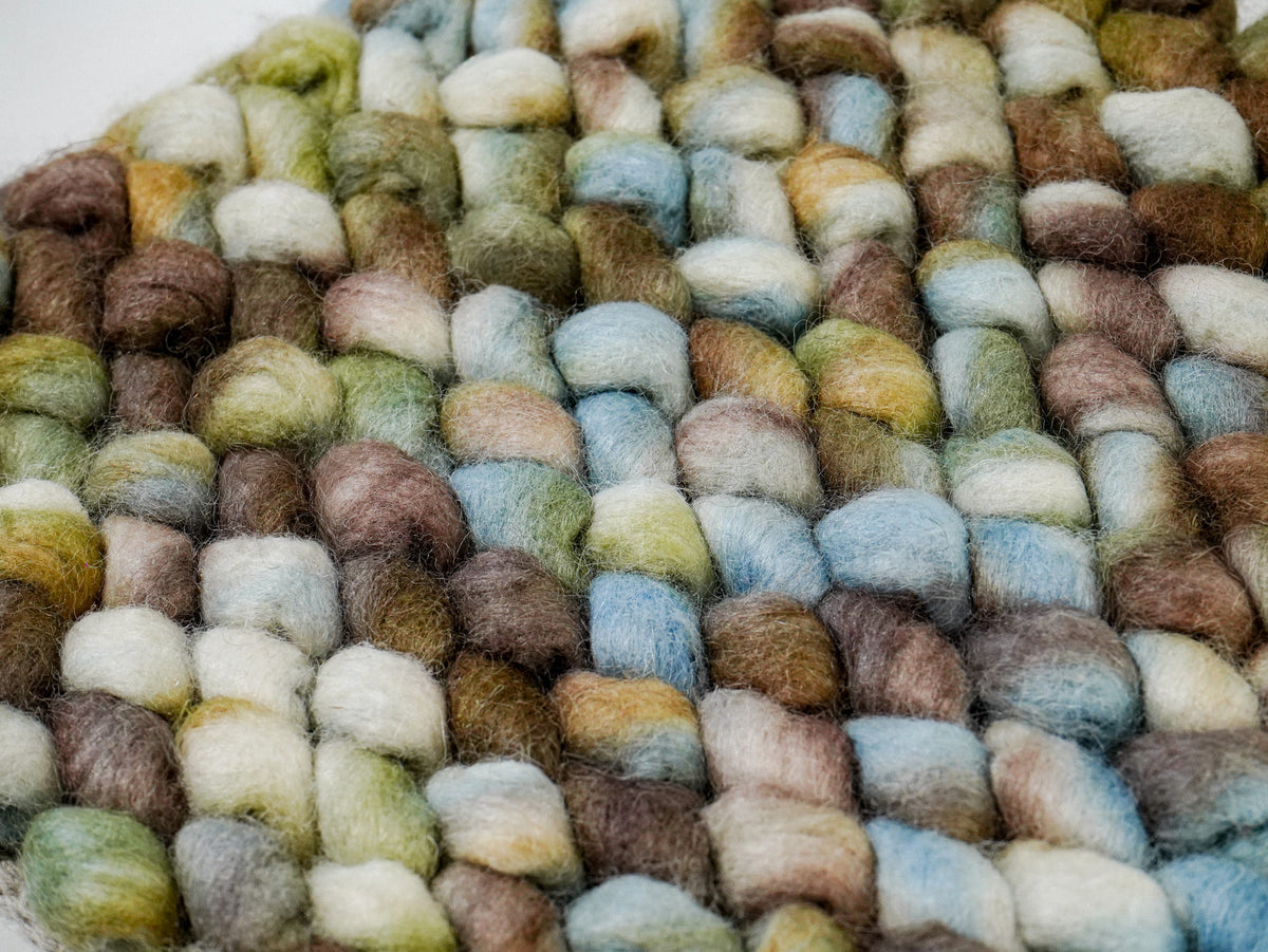 Multicolor Cashew Loop — Wool rug with blue, cream, green, and brown loops viewed diagonally