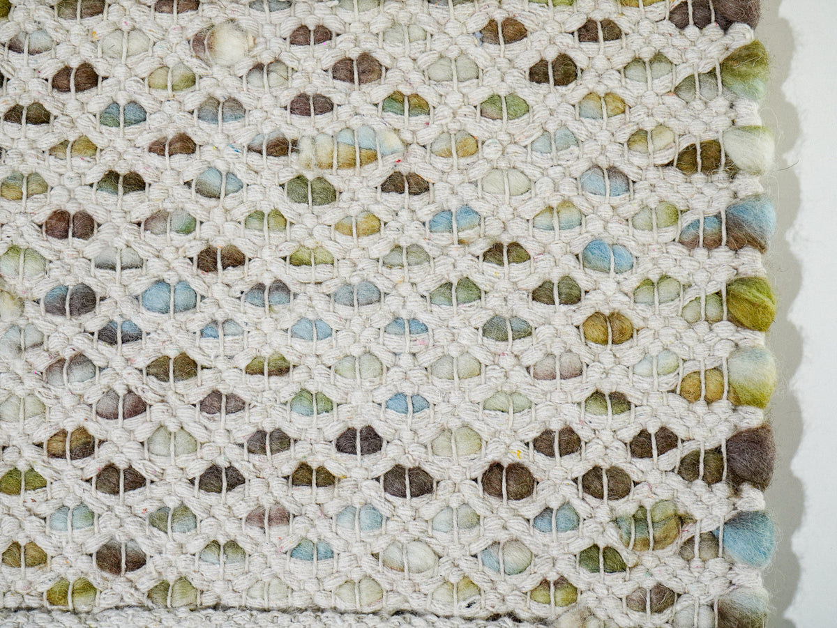 Multicolor Cashew Loop — Wool rug underside close-up showing the cream open weave and colored loops beneath