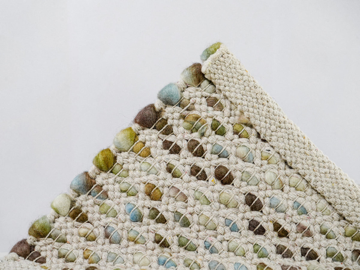 Multicolor Cashew Loop — Wool rug underside corner with a broad cream finishing band