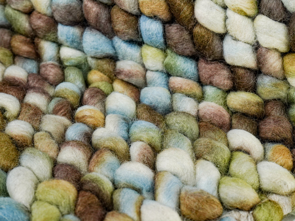 Multicolor Cashew Loop — Wool rug close-up across a fold with raised blue, green, and cream loops