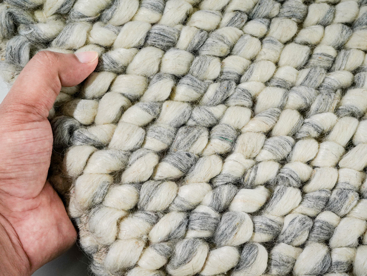 Gray Cashew Loop — Wool rug held in one hand to show the chunky loop surface