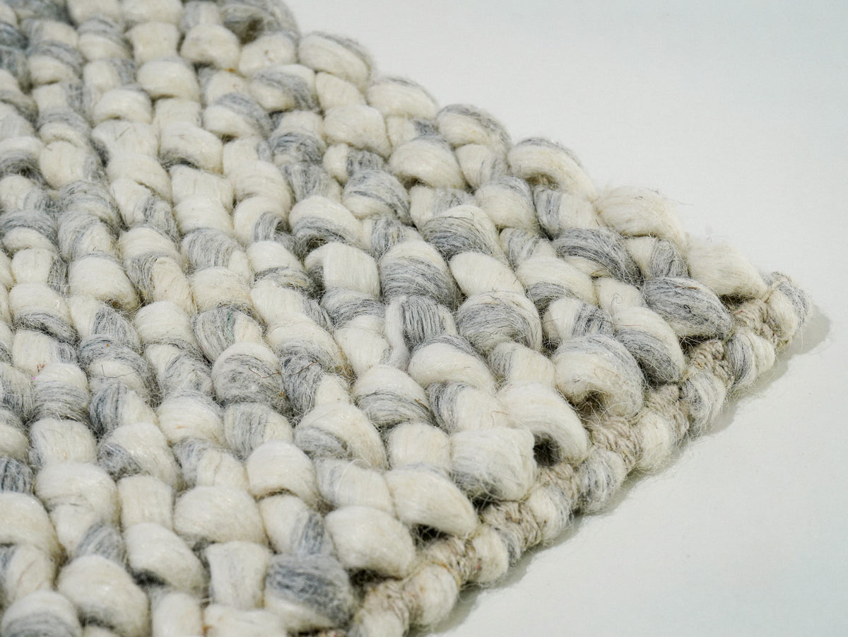 Gray Cashew Loop — Wool rug viewed at a low angle across the raised surface and right corner