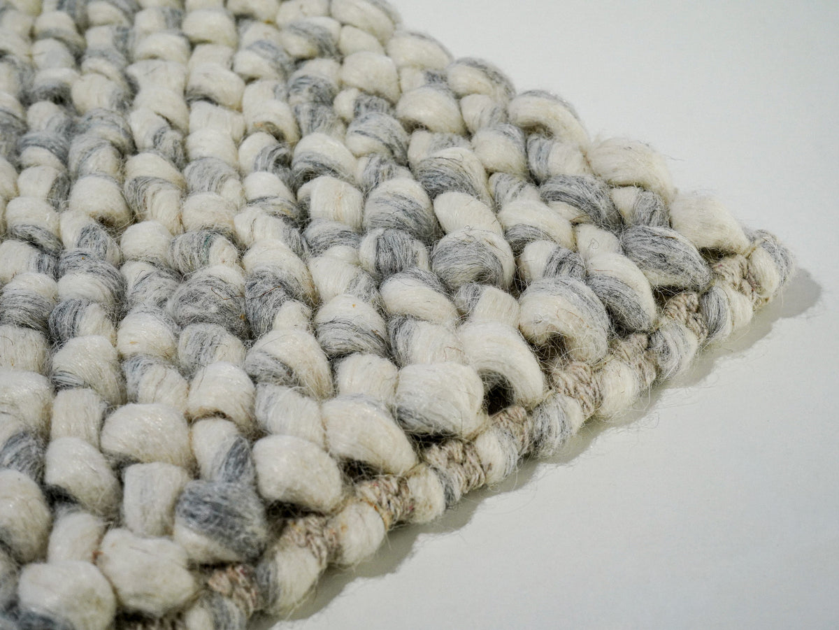 Gray Cashew Loop — Wool rug with an angled close-up of the front edge and corner