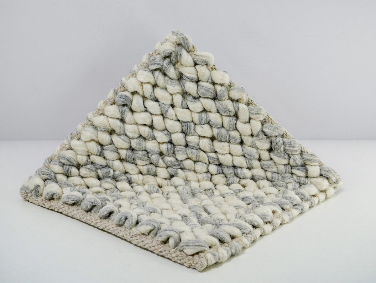 Gray Cashew Loop — Wool rug folded upright to show the surface and underside along the front edge
