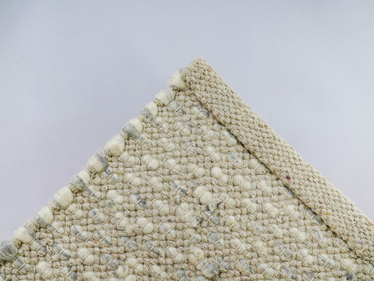 Gray Cashew Loop — Wool rug showing the reverse weave and finished edge of a lifted corner